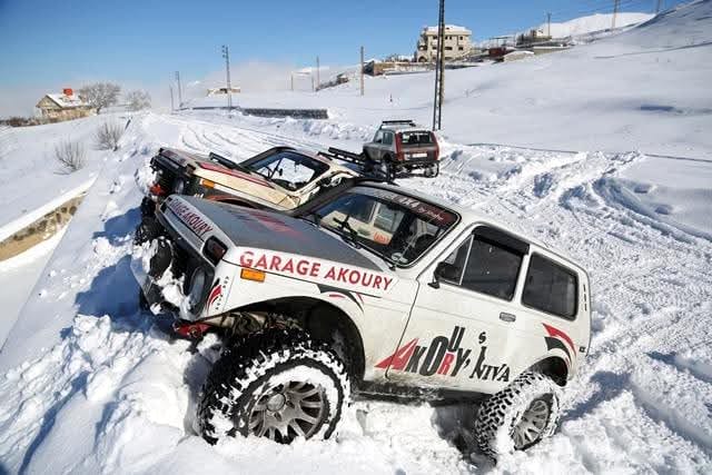 Wissam Akoury's Niva on a snow-covered mountain trail, surrounded by deep snow, with another off-road vehicle nearby.